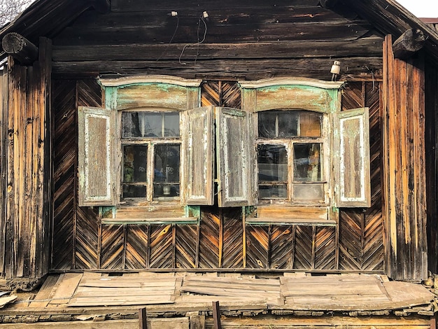 Zwei Fenster eines alten Holzhauses im Dorf