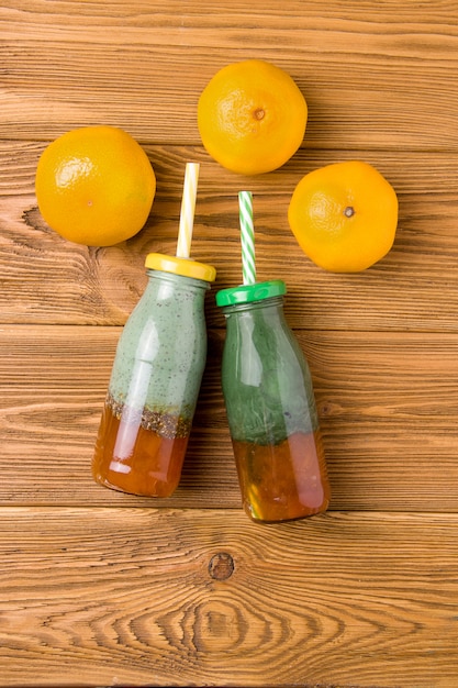 Zwei Flaschen mit einem Getränk von Spirulina Joghurt und Zitrusmarmelade auf einem hölzernen Hintergrund