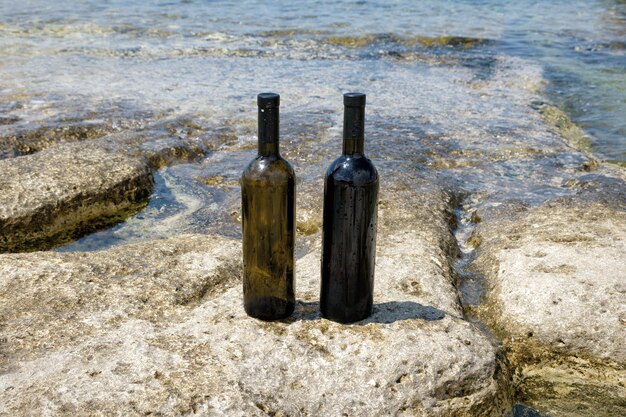 Foto zwei flaschen wein am felsigen ufer des kaspischen meeres