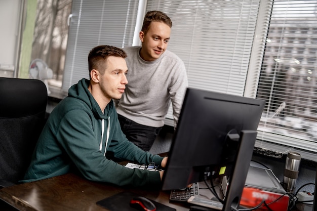 Zwei fokussierte Mitarbeiter sitzen zusammen an einem Tisch in einem modernen Büro