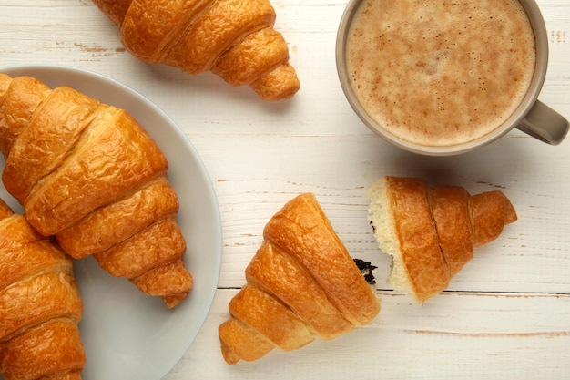 Zwei französische Croissants auf Teller und Tasse Kaffee auf weißem Hintergrund