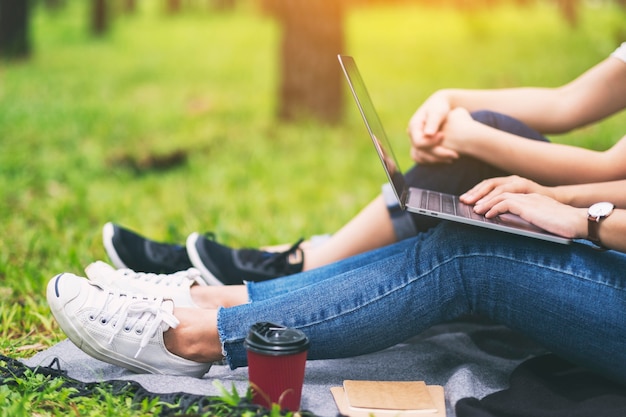 Foto zwei frauen arbeiten und benutzen laptop-computer, während sie im park sitzen