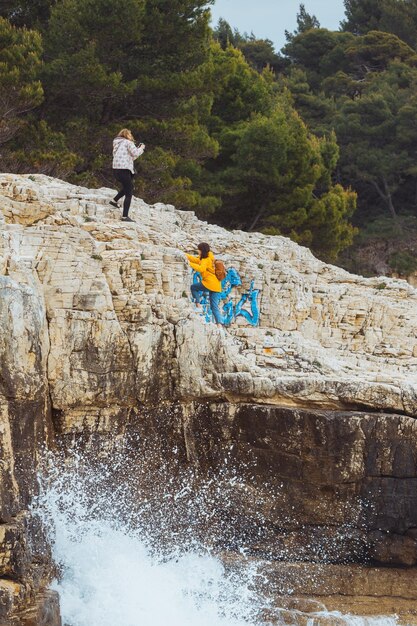 Zwei Frauen, die durch Felsen an der felsigen Küste klettern