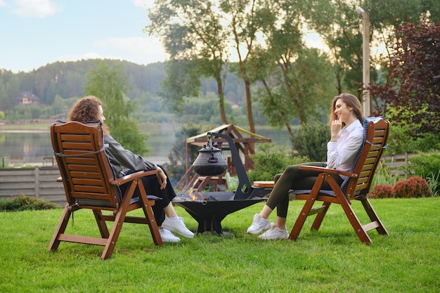 Zwei Frauen entspannen sich im Hinterhof, sitzen auf Stühlen und unterhalten sich