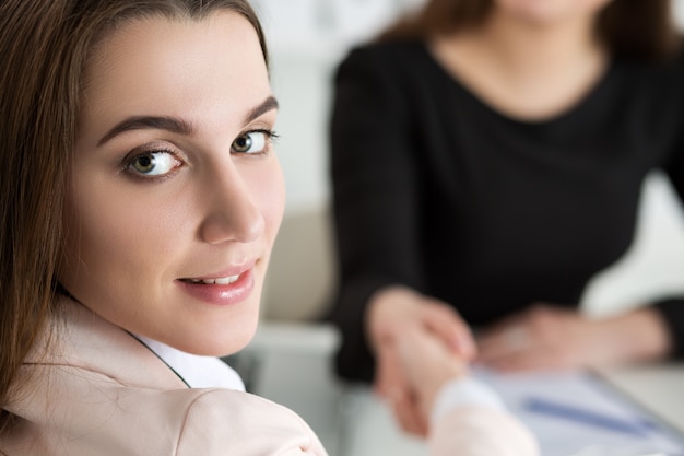 Zwei Frauen Händedruck im Büro Geschäftsfrauen Händeschütteln Lady blickt über die Schulter zurück Partnerschaftsgeschäft und Kollaborationskonzept Partner machten Deal Formale Begrüßungsgeste