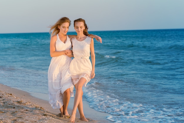 Zwei Frauen in einem weißen Kleid am Strand