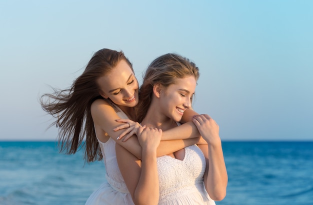 Zwei Frauen in einem weißen Kleid am Strand