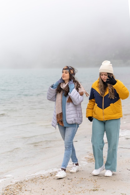 Zwei Frauen in warmer Kleidung, die im Winter neben einem See auf einem Gletscher spazieren