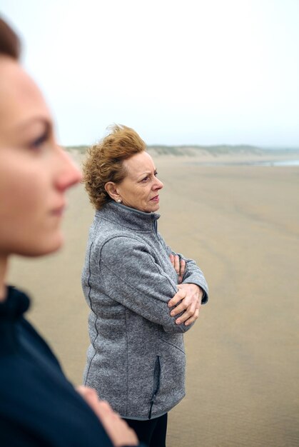 Zwei Frauen mit Blick auf das Meer am Strand im Herbst Selektiver Fokus auf Frau im Hintergrund