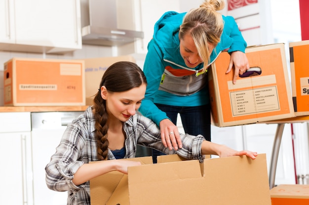 Zwei Frauen mit Umzugskarton in ihrem Haus