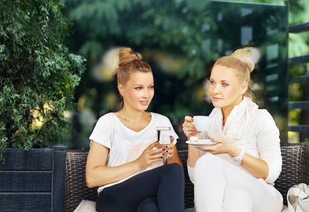 Zwei Frauen mittleren Alters nutzen im Freien ein Smartphone und ein Tablet