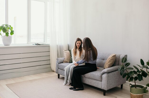 Zwei Frauen sitzen in einem Zimmer auf einem Sofa und unterhalten sich. Ein herzliches Gespräch. Vertrauen Sie einer Person. Weibliche Freundschaft