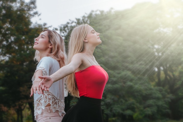 Zwei Frauen stehen und erheben sich die Hände im Park Beste Freunde