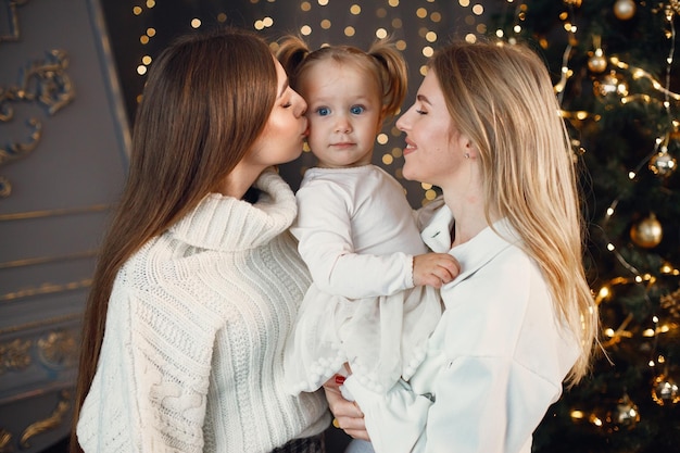 Zwei Frauen und ein kleines Mädchen stehen in der Nähe des Weihnachtsbaums und umarmen sich