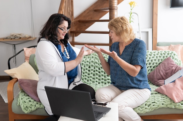 Zwei Frauen unterhalten sich auf der Couch sitzend