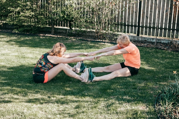 Zwei Frauen zwischen 55 und 59 Jahren kommunizieren in der Natur auf grünem Gras und treiben Sport