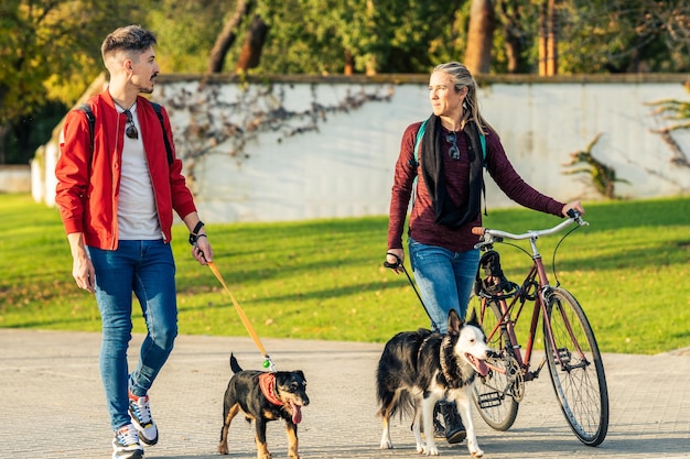 Zwei Freunde gehen mit dem Hund an der Leine in einem Park neben einem See spazieren