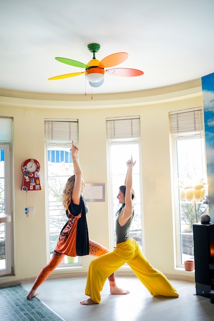 Zwei Freunde genießen ihre Yogastunde zu Hause in einer Kriegerposition