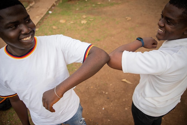 Foto zwei freunde in afrika begrüßen sich mit ellbogen, um den kontakt während der coronavirus-pandemie zu reduzieren neues normales konzept