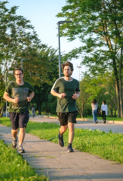 Zwei Freunde laufen mit grünem T-Shirt im Park