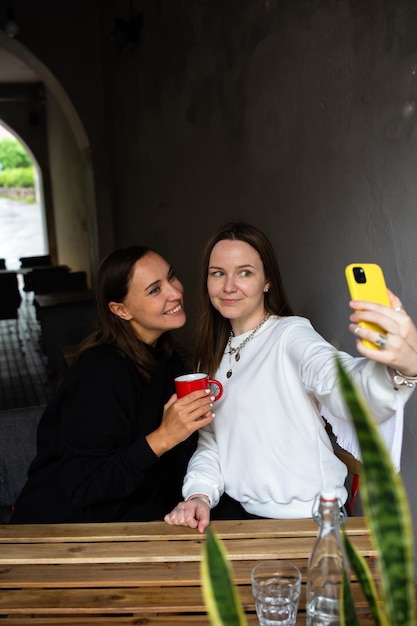 Foto zwei freundinnen amüsieren sich im freien in einem café und machen ein selfie mit einem smartphone