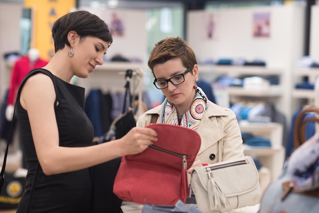 Zwei Freundinnen beim Einkaufen im Einkaufszentrum mit Taschen und Auswahl