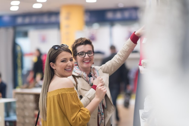 Zwei Freundinnen beim Einkaufen im Einkaufszentrum mit Taschen und Auswahl