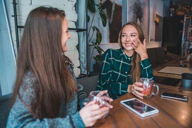 Zwei Freundinnen, die im Café sprechen, während sie einen Tee trinken. Tagungskonzept