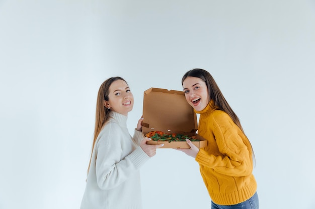 Zwei Freundinnen essen Pizza.