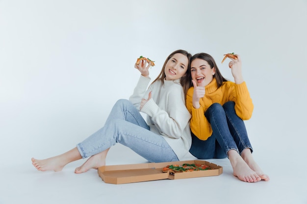 Zwei Freundinnen essen Pizza.