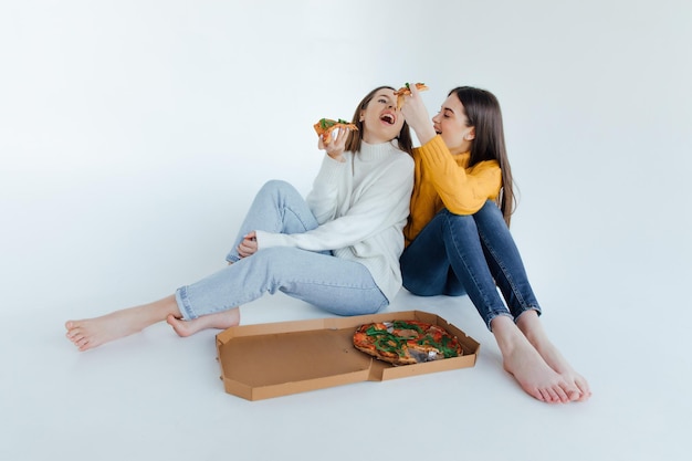 Zwei Freundinnen essen Pizza.