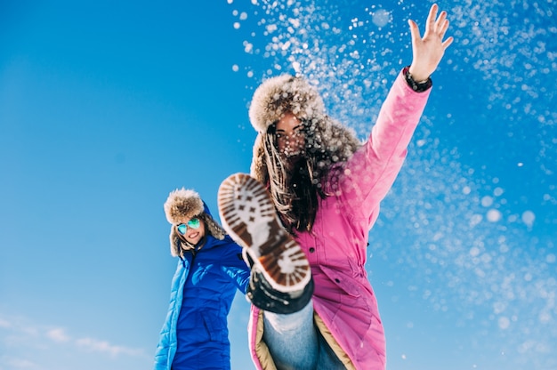 Zwei Freundinnen haben Spaß und genießen den frischen Schnee an einem schönen Wintertag in den Bergen