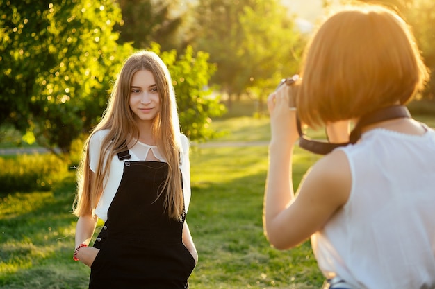 Zwei Freundinnen im Park fotografieren mit einer professionellen Kamera. Fotoshooting Fotosession in der Stadt