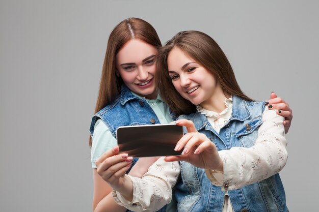 Zwei Freundinnen in Jeansjacken machen Selfie