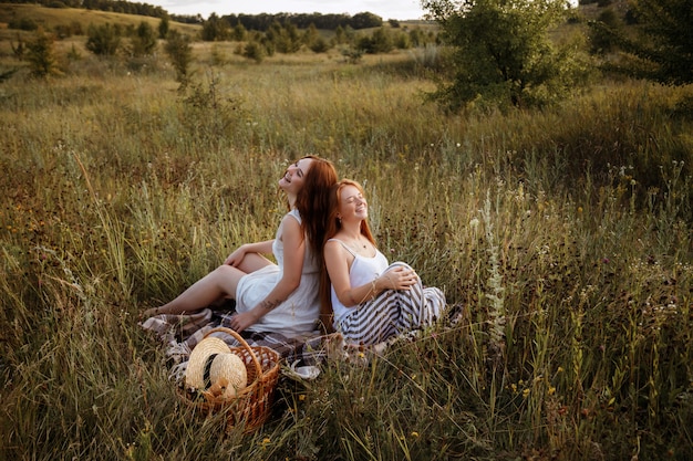 Zwei Freundinnen sitzen auf dem Feld. Picknick von zwei Freundinnen. Glück