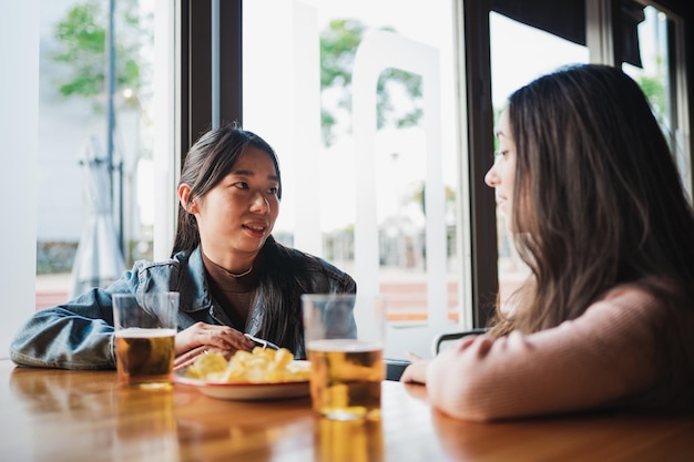 Zwei Freundinnen unterhalten sich bei einem Snack und einem Bier in einer Bar