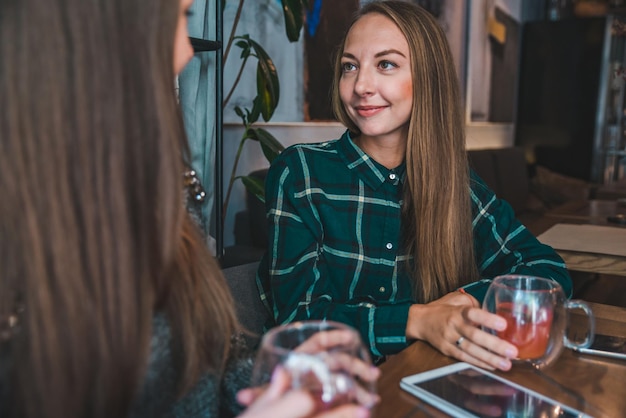 Zwei Freundinnen unterhalten sich im Café, während sie ein Teetreffen trinken