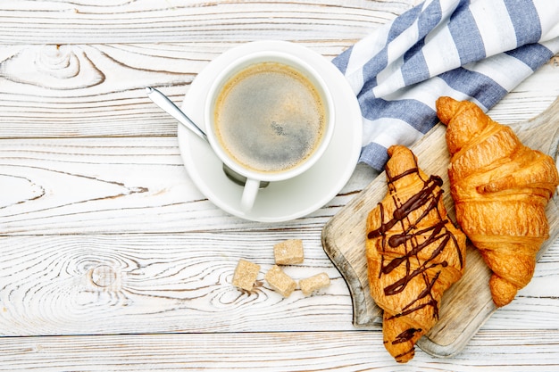 Zwei frische Croissants und Kaffee auf hölzernem Hintergrund