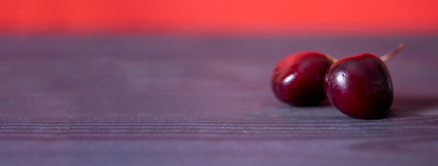 Zwei frische Kirschen auf einem dunklen Holztisch mit Kopienraum