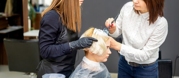 Zwei Friseure, die Haare der Frau färben