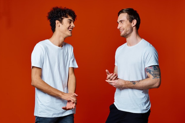 Zwei fröhliche Freunde in weißen T-Shirts stehen Seite an Seite vor isoliertem Hintergrund