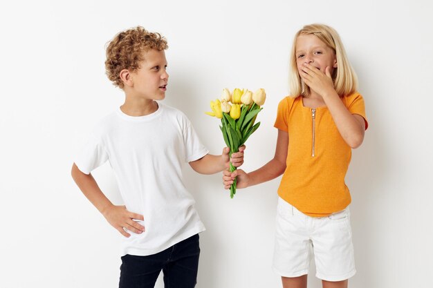 Zwei fröhliche Kinder mit einem Blumenstrauß Geschenk Geburtstag Urlaub Kindheit hellen Hintergrund