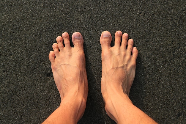 Zwei Fuß am Strand. mit braunem schwarzen Sandstrand