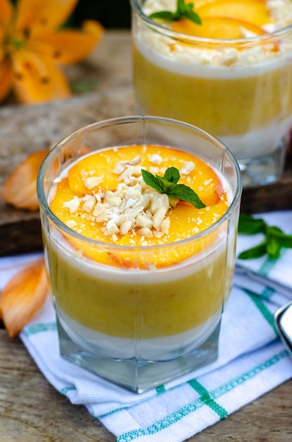 Zwei Galassen Pfirsich-Panna-Cotta mit weißen und orangefarbenen Schichten.