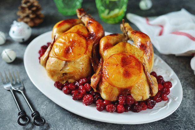 Zwei ganze Brathähnchen mit Preiselbeeren und Orangenscheiben