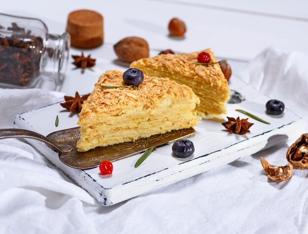 Zwei gebackene Kuchen Napoleon mit Sahne auf einem weißen hölzernen Brett