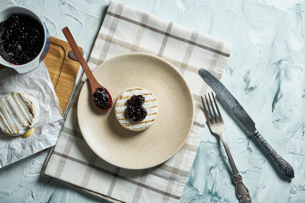 Zwei gegrillte Camembertkäseköpfe auf Teller und auf Schneidebrett mit Marmelade. leichte Textur Tabelle.