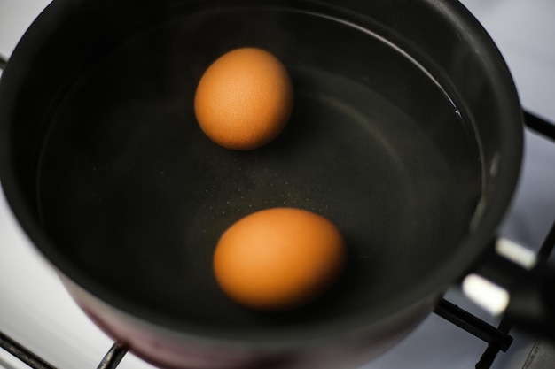Zwei gekochte braune Eier in einem Topf mit kochendem Wasser