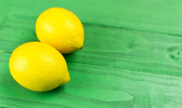 Zwei gelbe Zitronen auf grünem Holzhintergrund