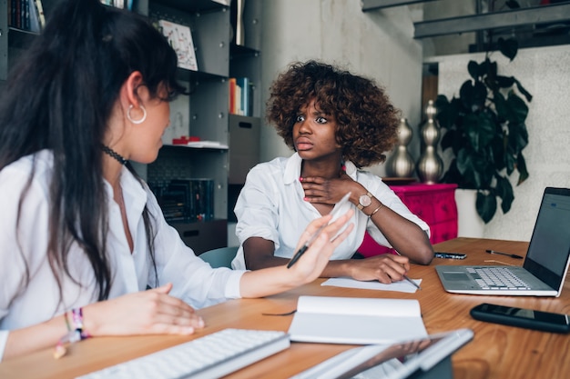 Zwei gemischtrassige Studenten diskutieren ein Projekt in einem Büro, in dem sie zusammenarbeiten